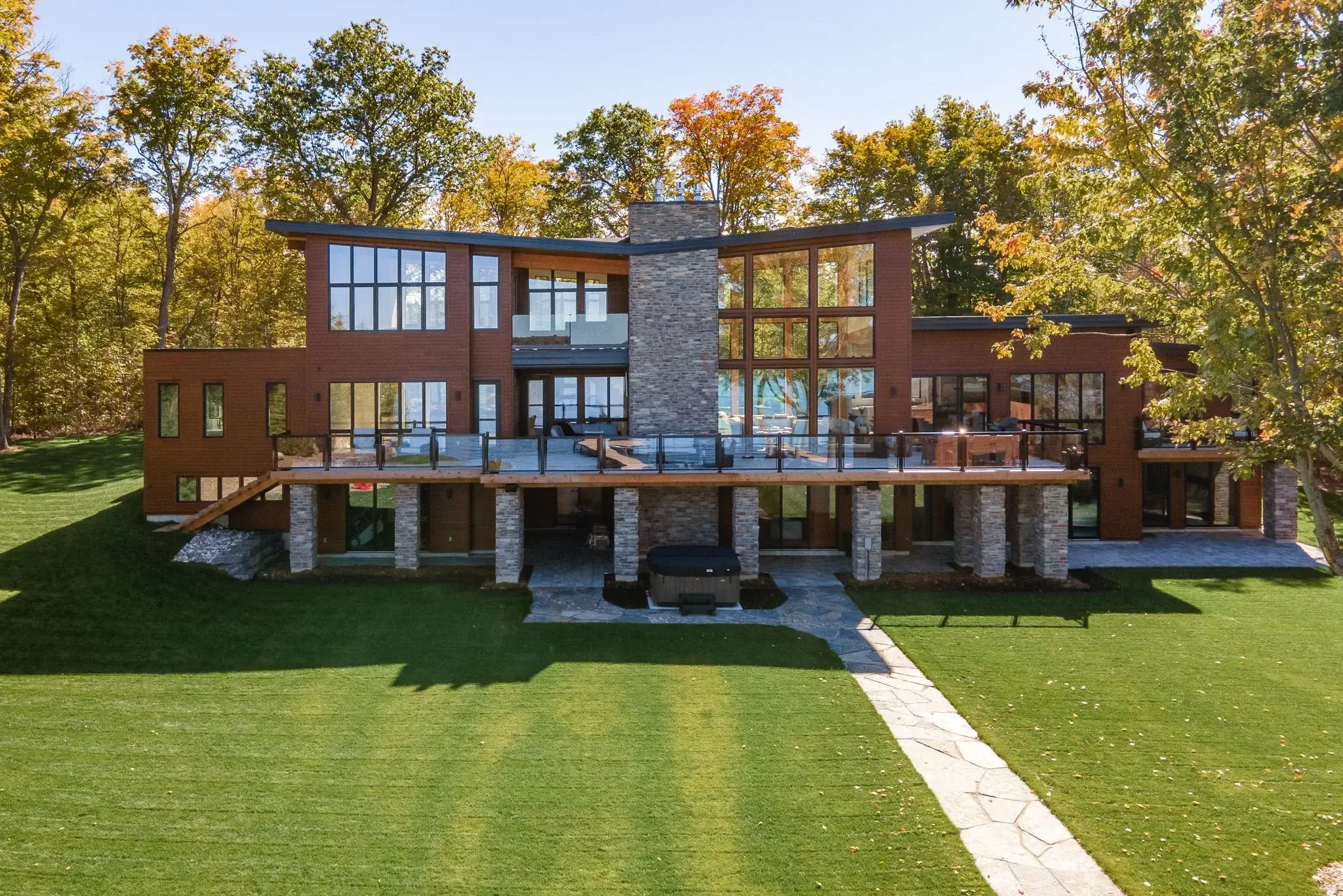 The View on Balsam: rear exterior from the lawn, wood siding and stone columns under an autumn sky