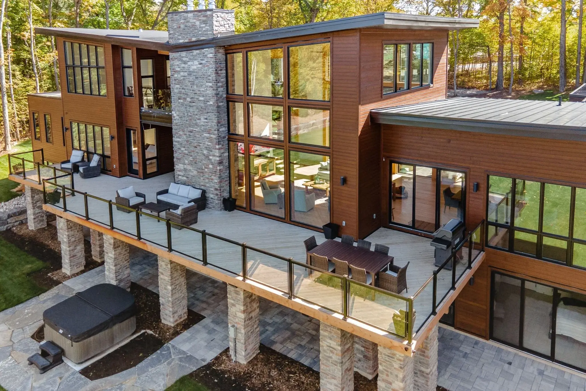 The View on Balsam: aerial view of the deck, stone chimney and glass railings above the treeline