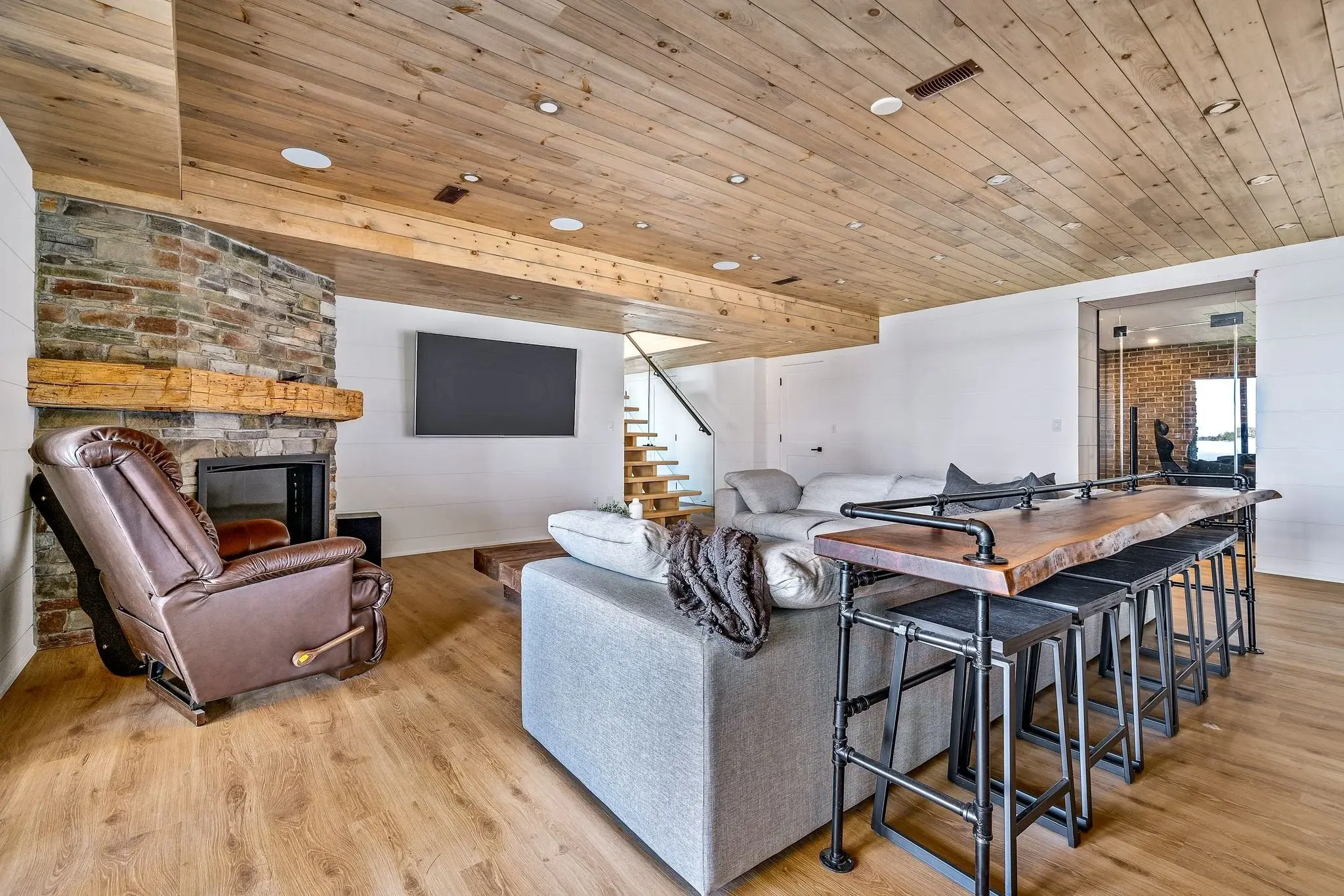 The View on Balsam: lower-level family room with stone fireplace beside the staircase